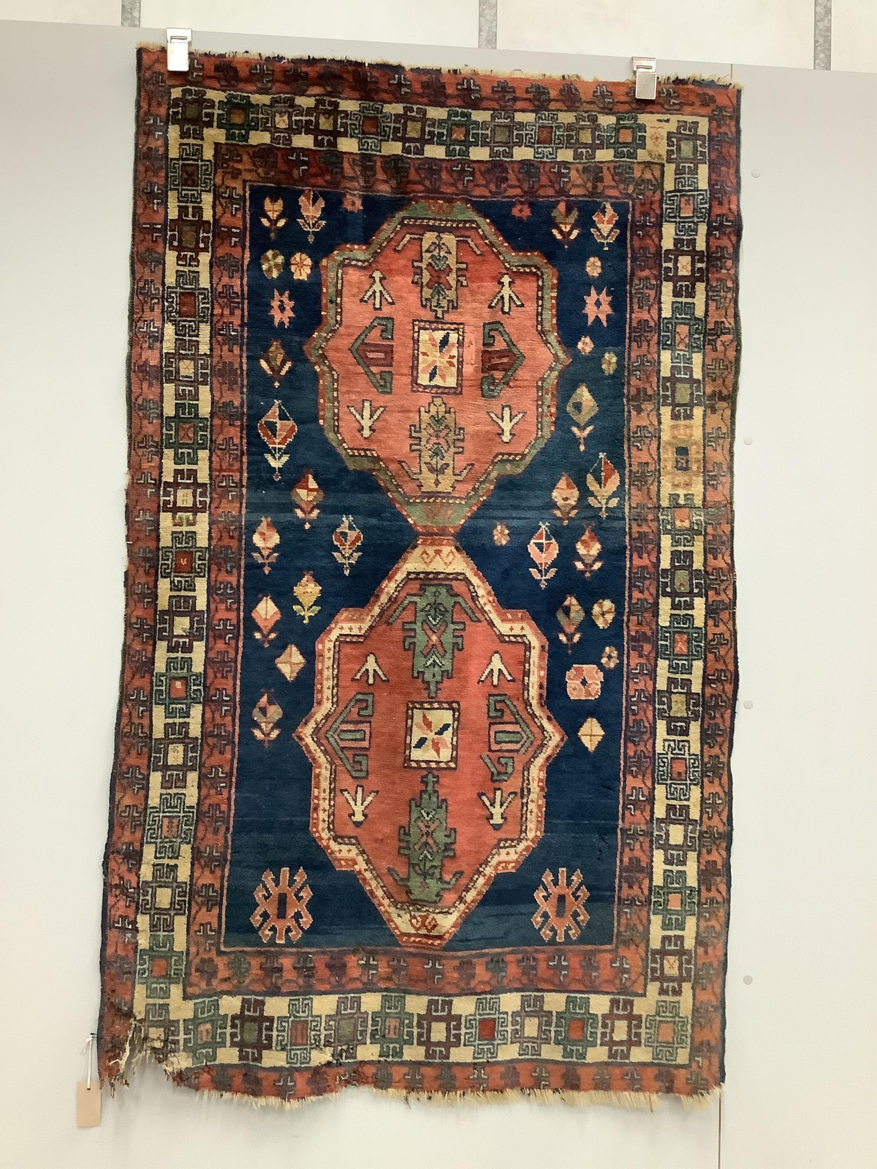 A Caucasian style blue ground twin medallion rug .160 x 97cm. Condition - poor, worn with losses to one corner